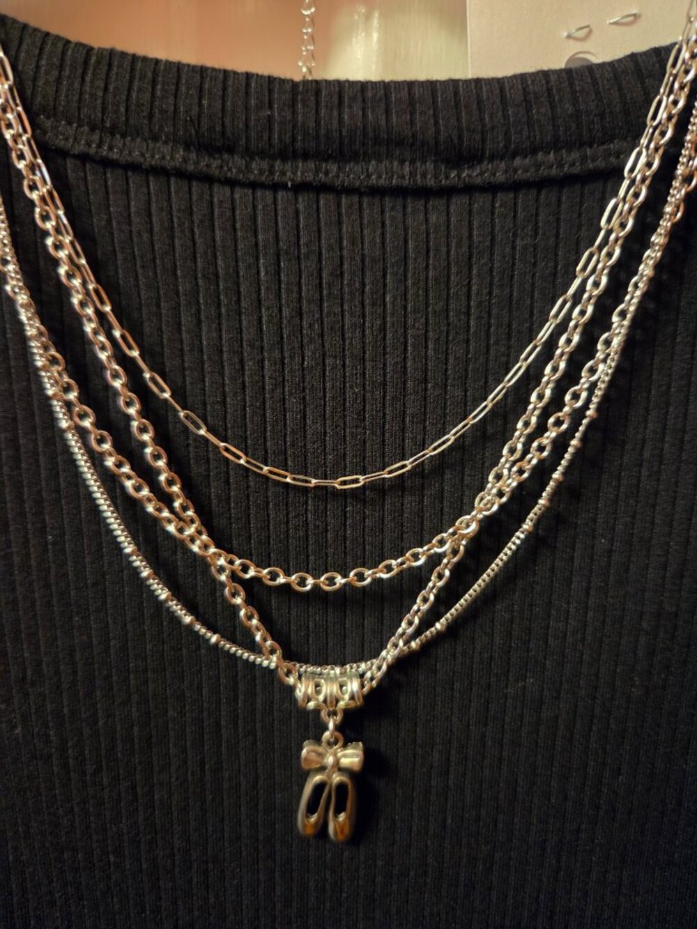Multiple slivertone Necklaces one has a pair of Ballet Slippers.